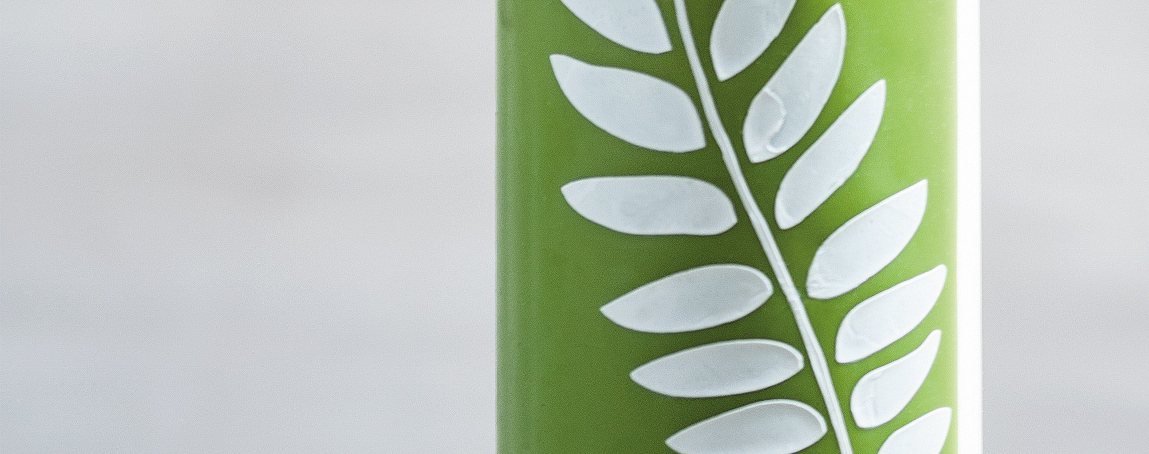 Green decorative candle with a white leaf
