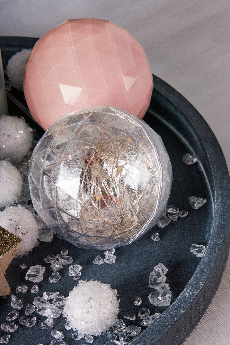 Salmon-coloured and glowing ball on a wooden tray