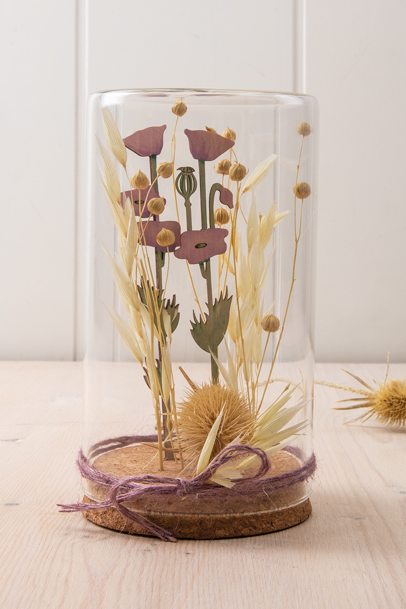 Trockenblumen und Holzstecker im Glasgefäß
